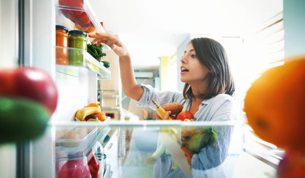 Closeup of a cheerful young couple picking some fruit and veggies from the fridge